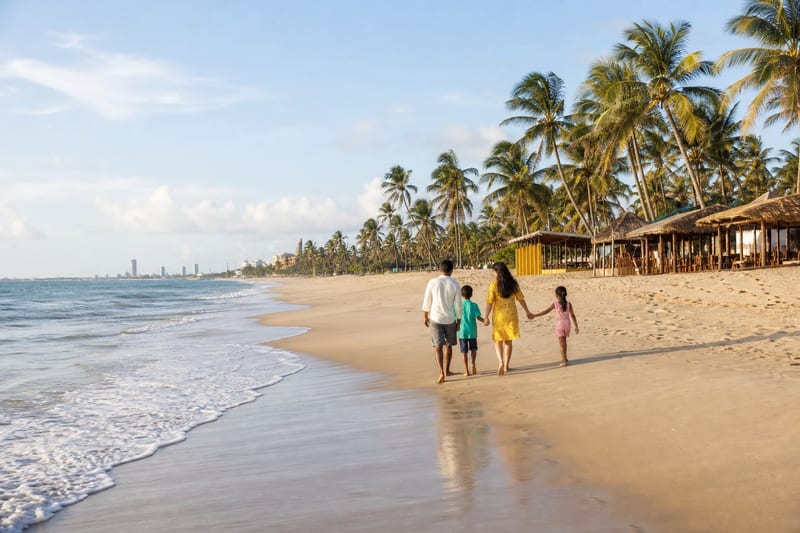 Familia caminhando na Praia do Futuro perto das barracas de praia